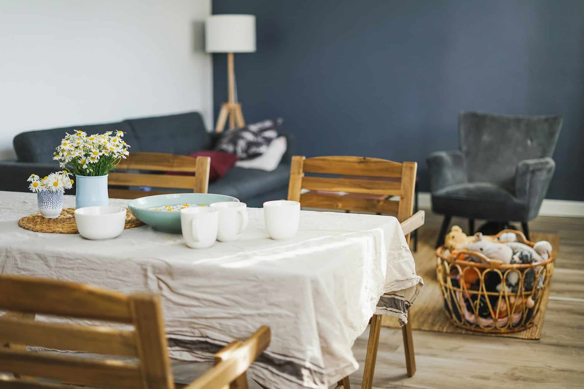 Table with flowers chamomile on linen tablecloth in living room